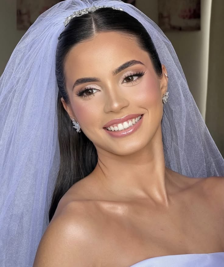 Noiva com maquiagem profissional, cabelo preso e véu em retrato frontal